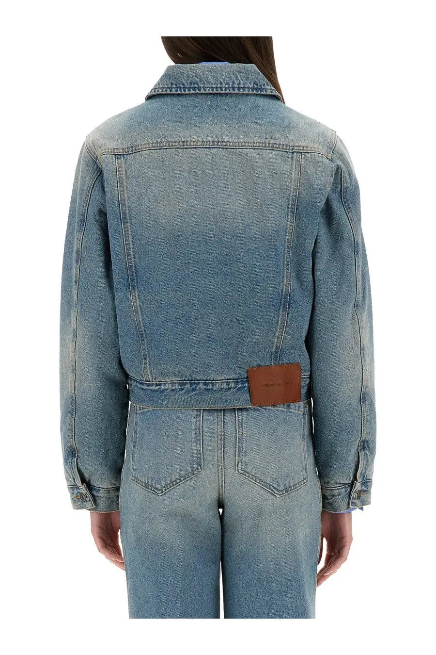 Victoria Beckham women’s blue light-wash denim jacket with classic collar and brown leather patch at the waist