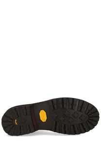 Black rubber sole with yellow vibram logo and deep tread on visvim men’s brown leather boot back side