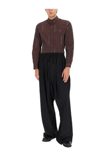A man wearing a dark brown and black vertically striped shimmering shirt with Vivienne Westwood men’s black balloon pants