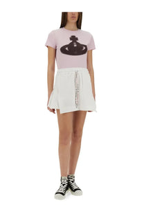 Pink short-sleeved t-shirt with black orb logo paired with Vivienne Westwood women’s white cheerleader skirt