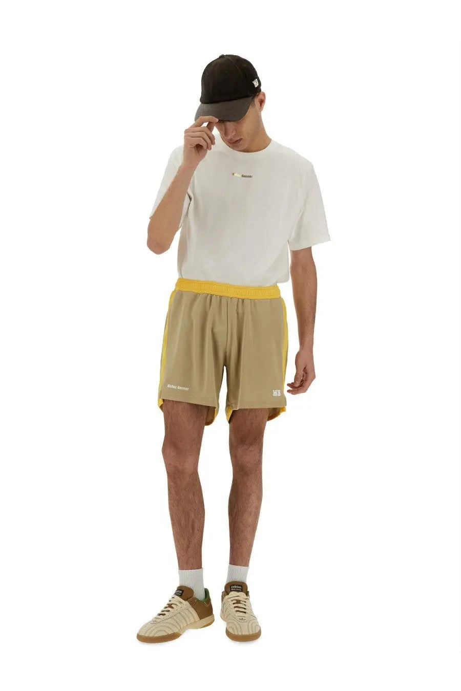 Khaki athletic shorts with yellow side panels and waistband featuring a subtle brand logo on the lower leg