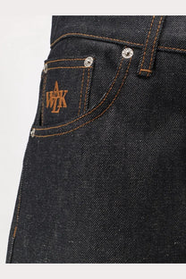 Back side of walk in paris men’s baggy blue denim jeans featuring dark blue denim with brown embroidered logo and silver rivets