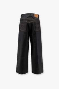 Back side of walk in paris men’s baggy blue denim jeans black showing dark indigo wide-leg pants with embroidered w logo and leather patch