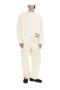 Cream-colored cable knit cardigan with black arrow logo on left chest paired with off-white men’s beige cargo pants