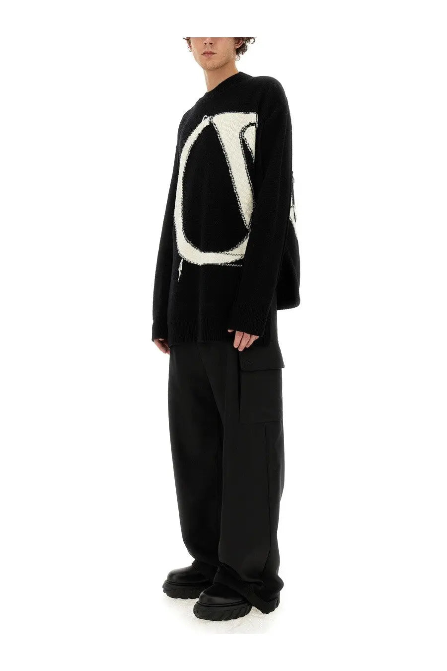 Off-white men’s cargo pants black paired with a black knit sweater featuring a bold white abstract logo design