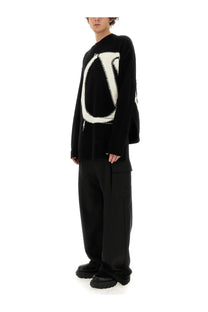 Off-white men’s cargo pants black paired with a black knit sweater featuring a bold white abstract logo design