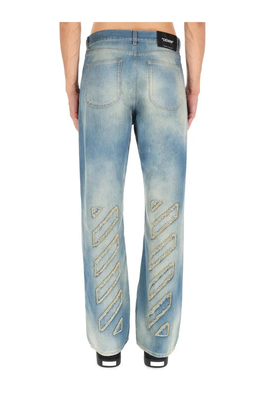Off-White men’s light-wash denim jeans featuring gold-tone embroidered zigzag patterns on the outer legs
