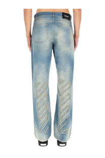 Off-White men’s light-wash denim jeans featuring gold-tone embroidered zigzag patterns on the outer legs