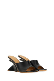 Off-White women’s black leather mules with a distinctive geometric wedge heel shown from the back side