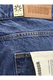 Blue denim jeans for men by woodbird featuring a tan leather brand patch and size w32 l32 white label on the back