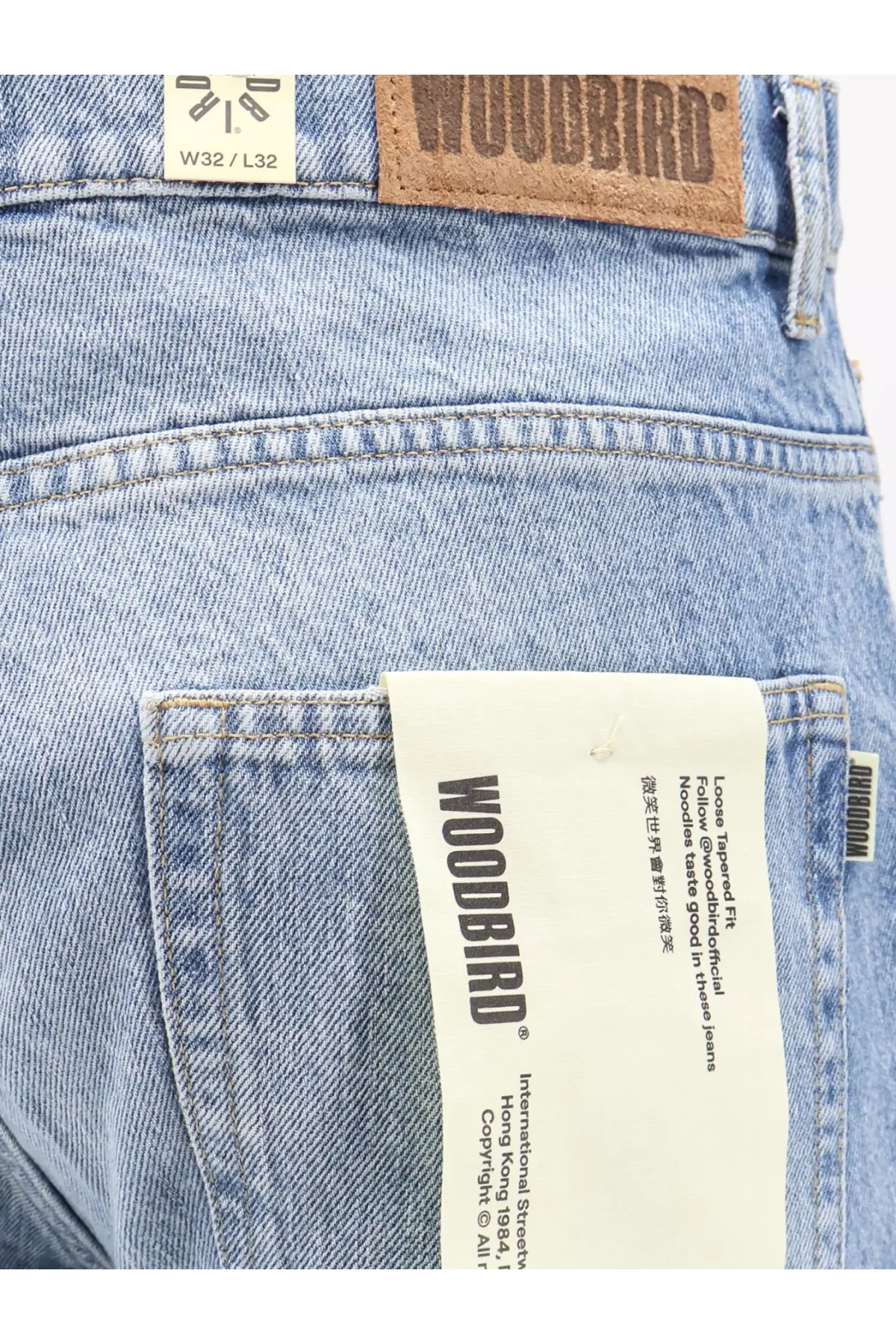 Woodbird men’s leroy denim jeans in light-wash blue with brown leather patch and white paper logo tag
