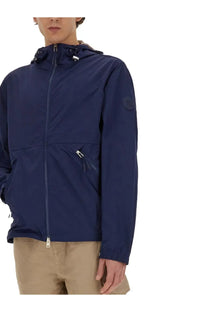 Woolrich men’s navy blue nylon jacket with waterproof hood and zippered pockets featuring a brand logo patch
