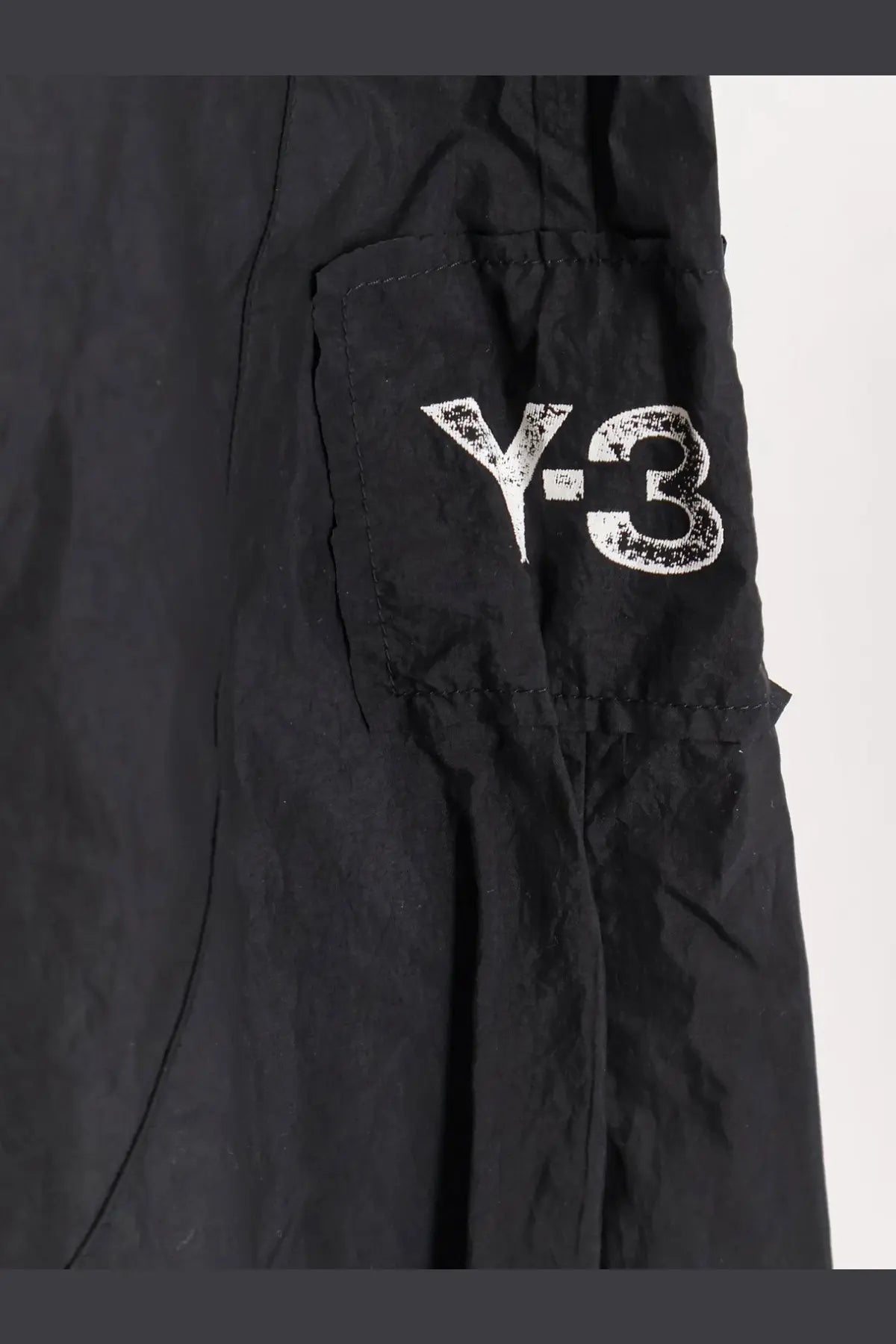 Black y-3 men’s baggy nylon cargo pants with a distressed white logo on the side pocket