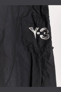 Black y-3 men’s baggy nylon cargo pants with a distressed white logo on the side pocket