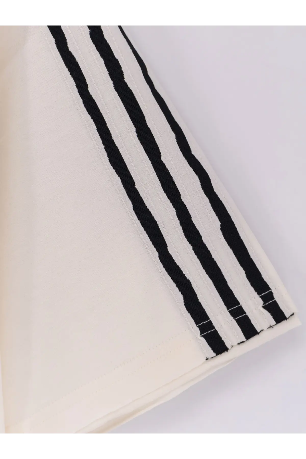 A cream-colored y-3 men’s cotton shirt with bold black vertical stripes and textured weave detailing