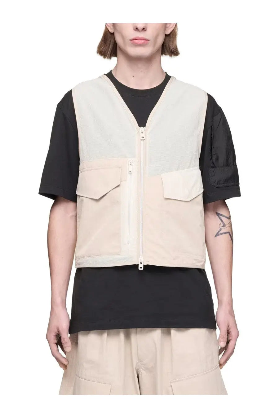 Y-3 men’s beige and black utility vest with front zipper closure, two chest flap pockets, and patchwork design