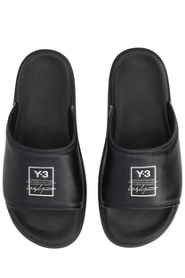 Black y-3 unisex slide sandals with a glossy finish and white logo branding on the footbed