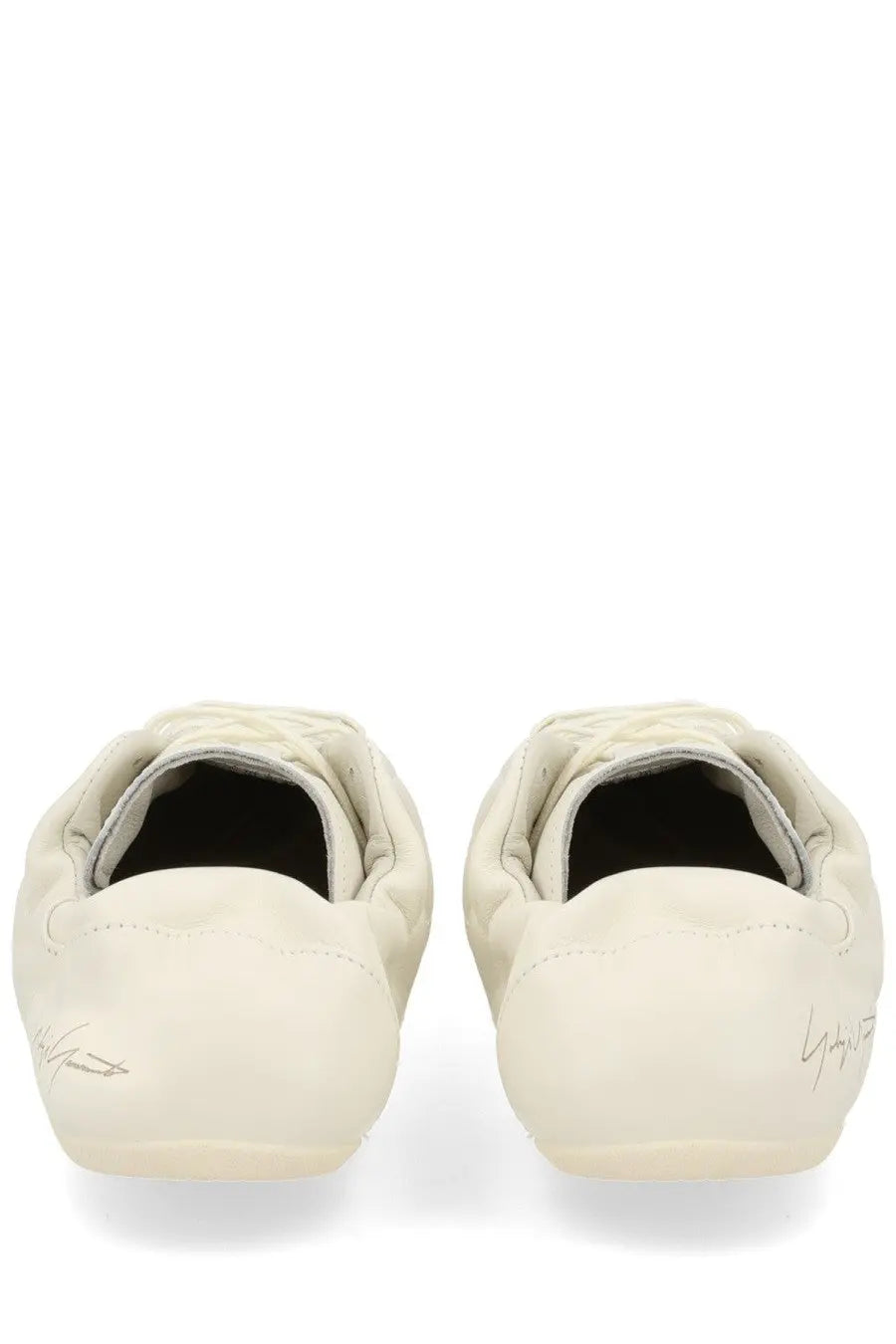 Cream-colored yohji yamamoto loafers with quilted detailing and signature branding on the heel back side