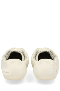 Cream-colored yohji yamamoto loafers with quilted detailing and signature branding on the heel back side