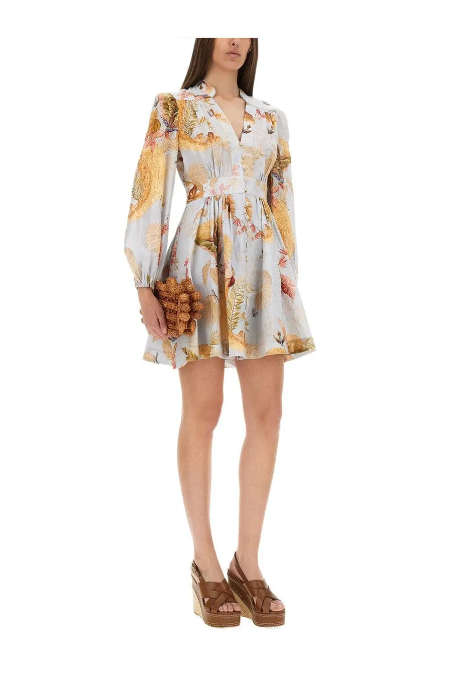 A woman wears a Zimmermann women’s Ascension dress in blue with gold floral print long sleeves and a fitted waist