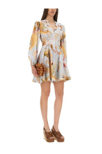 A woman wears a Zimmermann women’s Ascension dress in blue with gold floral print long sleeves and a fitted waist