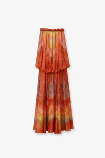 A flowing two-tiered maxi skirt in vibrant orange and yellow tie-dye with braided elastic waistband