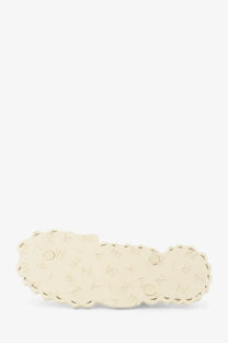 Cream-colored scalloped-edge hair clip with subtle embossed pattern complementing zimmermann seafoam thong sandals white